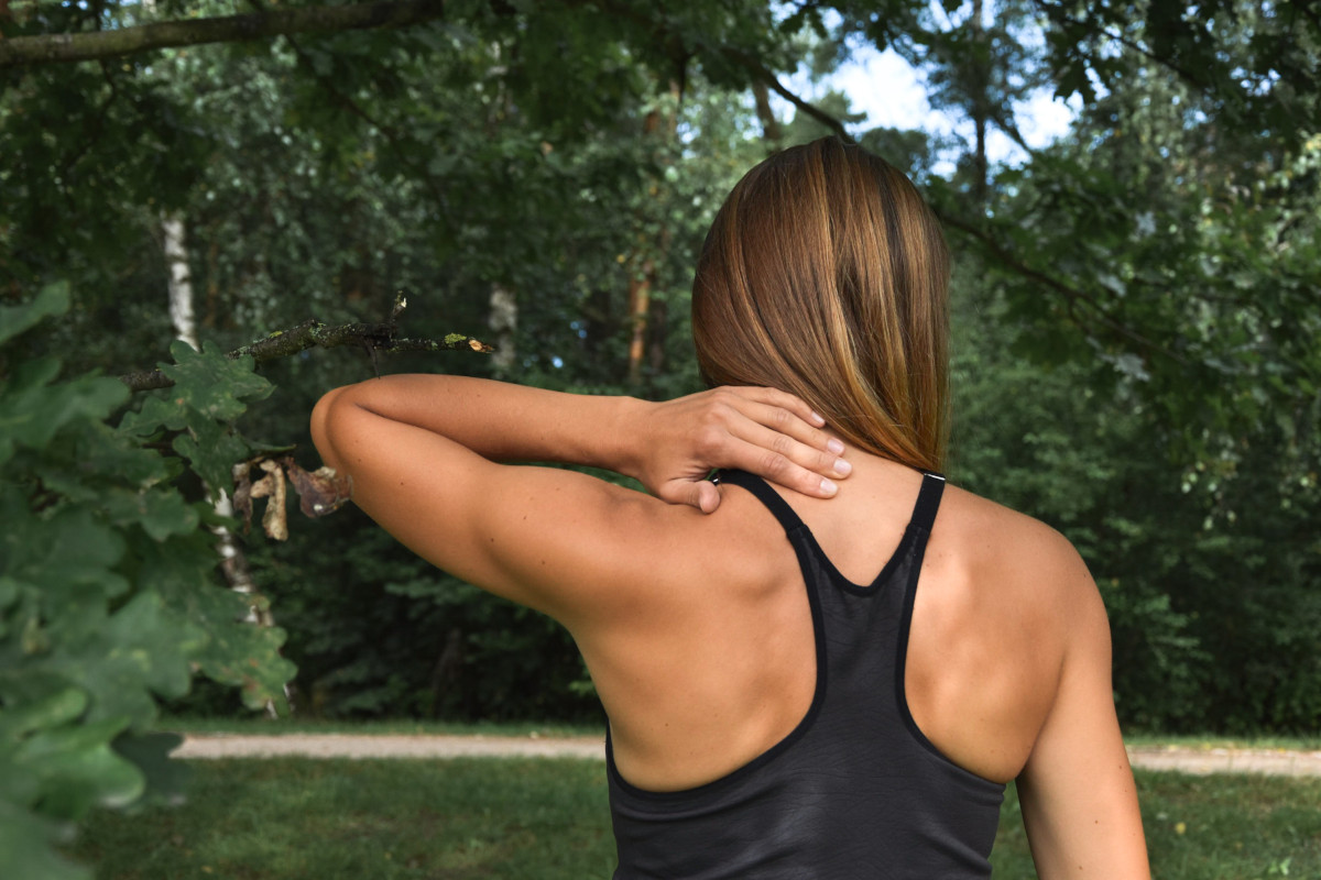 Ból kręgosłupa, odcinka szyjnego. Młoda kobieta podczas treningu fitness w parku doznała urazu. Back pain, cervical pain. A young woman was injured during a fitness workout in the park.